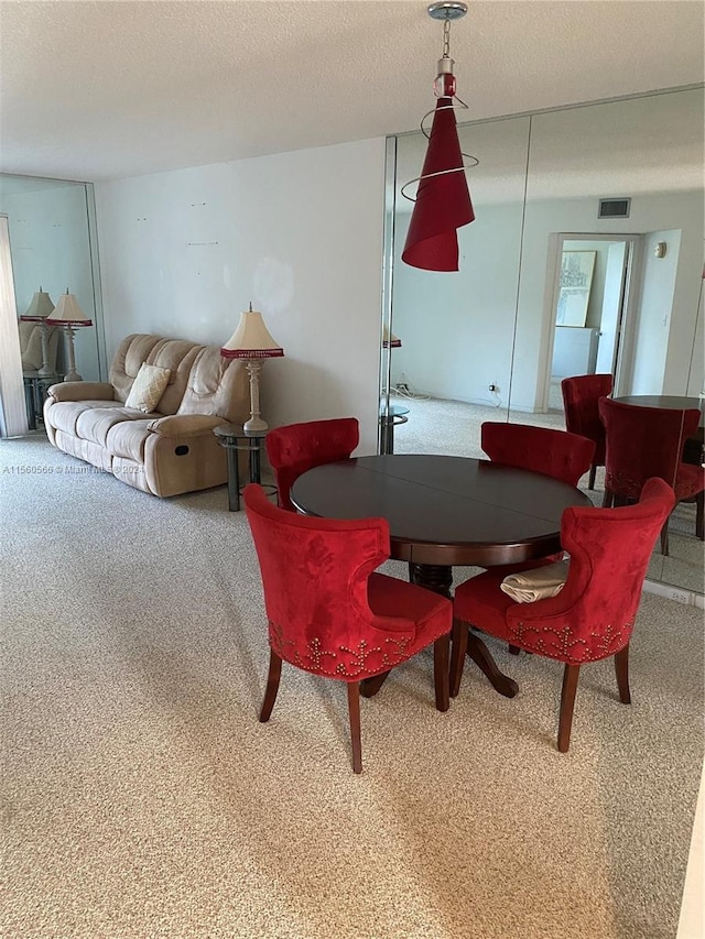 dining room featuring carpet and a textured ceiling