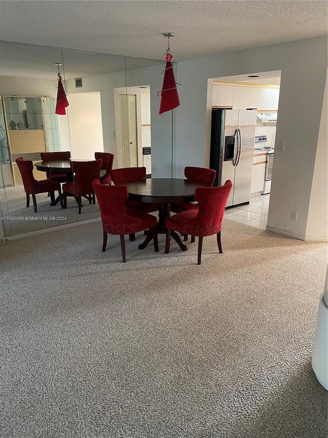 dining room featuring a textured ceiling and light carpet