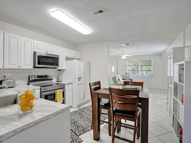 kitchen with white cabinetry, ceiling fan, stainless steel appliances, light tile floors, and a textured ceiling