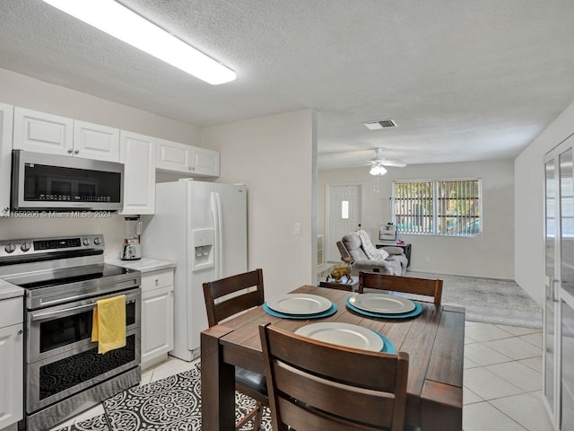 kitchen featuring white cabinets, appliances with stainless steel finishes, ceiling fan, and light tile floors