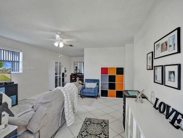 living room with light tile floors, a textured ceiling, and ceiling fan