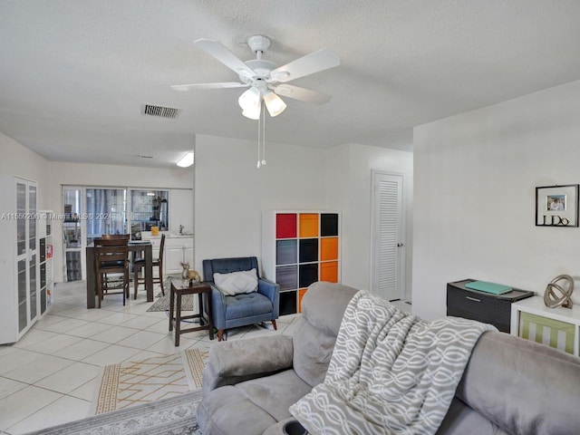 living room featuring light tile floors, ceiling fan, and a textured ceiling