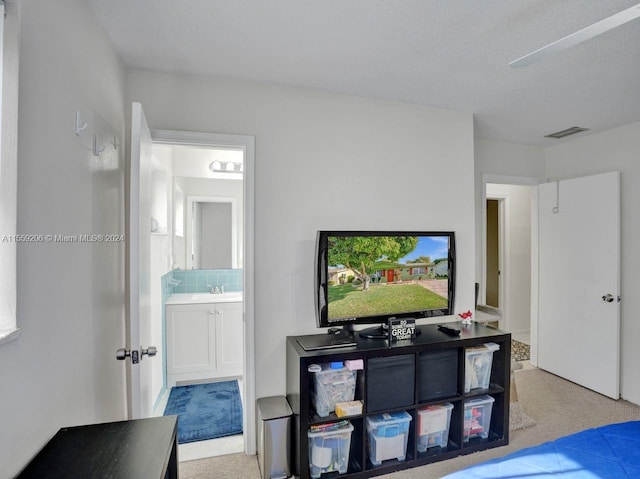 carpeted bedroom featuring ensuite bath, ceiling fan, and sink