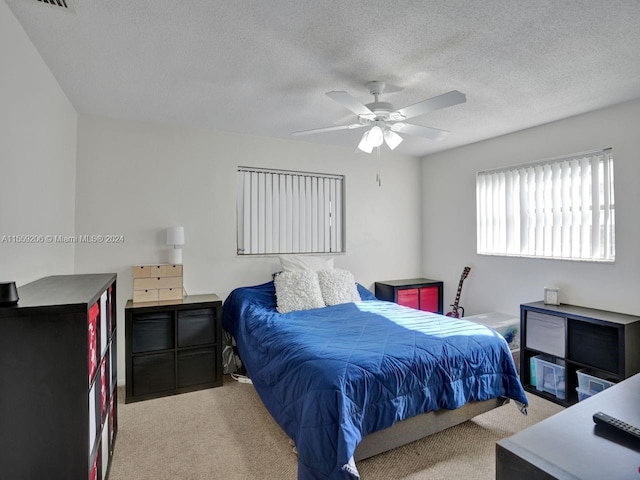 carpeted bedroom featuring ceiling fan and a textured ceiling