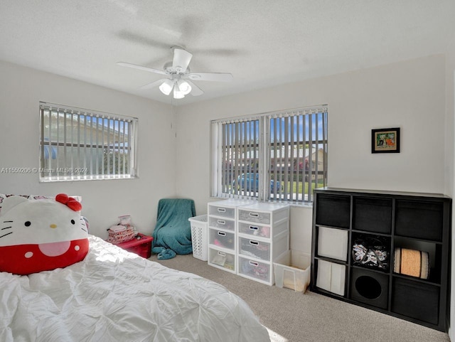 bedroom featuring a textured ceiling, ceiling fan, and light colored carpet