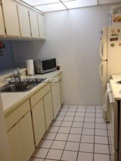 kitchen with stove, light tile patterned floors, and cream cabinetry