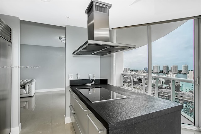 kitchen featuring high end fridge, black electric cooktop, light tile flooring, and island range hood