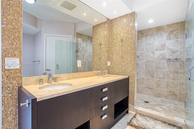 bathroom featuring tile floors, oversized vanity, a shower with shower door, and dual sinks