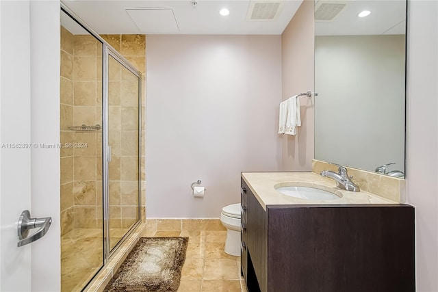 bathroom featuring toilet, a shower with door, tile floors, and vanity with extensive cabinet space