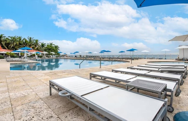 view of pool featuring a patio area and a water view