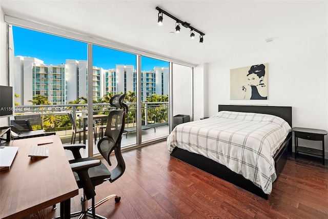 bedroom featuring floor to ceiling windows, access to outside, dark wood-type flooring, and rail lighting