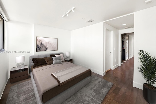 bedroom with track lighting and dark hardwood / wood-style flooring