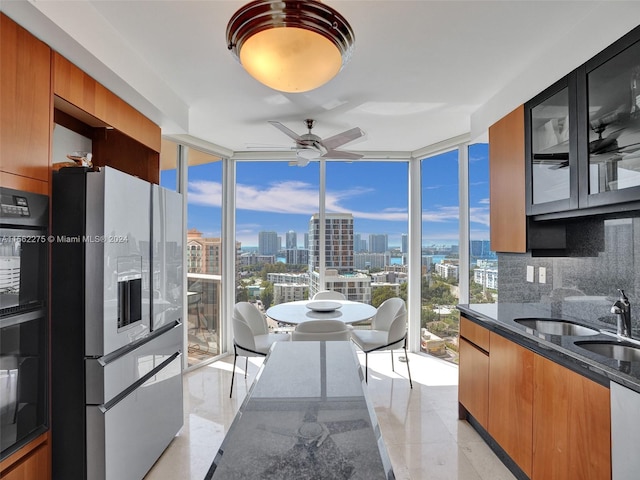 kitchen featuring stainless steel fridge, ceiling fan, floor to ceiling windows, dark stone countertops, and backsplash