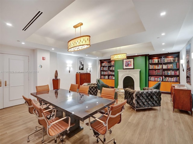 dining area with light wood-type flooring and a tray ceiling