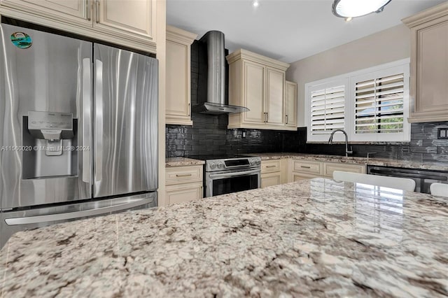 kitchen with backsplash, stainless steel appliances, cream cabinetry, wall chimney exhaust hood, and sink