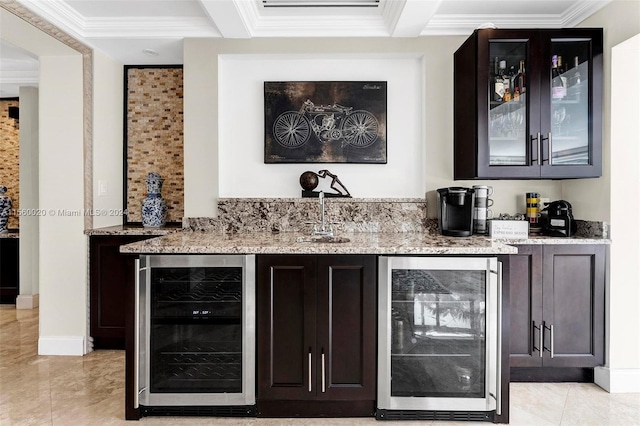 bar with light stone counters, dark brown cabinets, and beverage cooler