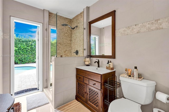 bathroom with tiled shower, toilet, and vanity