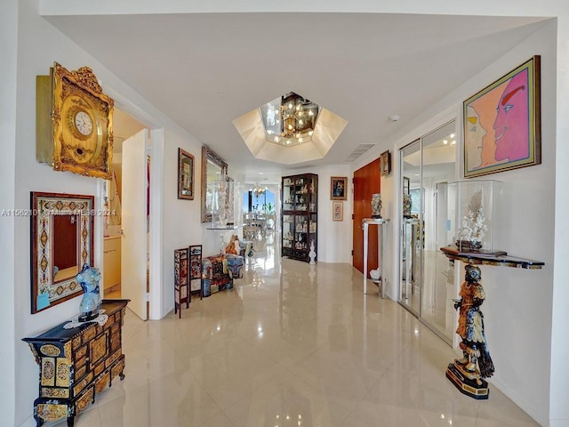 corridor featuring tile flooring and a chandelier