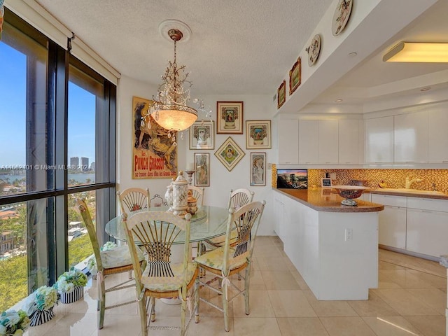 tiled dining room featuring sink, a tray ceiling, and a textured ceiling