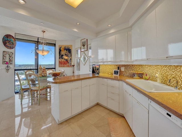 kitchen featuring kitchen peninsula, white cabinets, backsplash, and white dishwasher