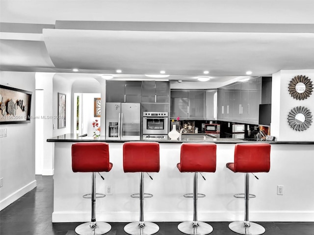 kitchen with gray cabinetry, a kitchen bar, and stainless steel appliances