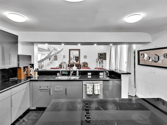 kitchen with dark tile floors, stainless steel dishwasher, sink, and dark stone countertops