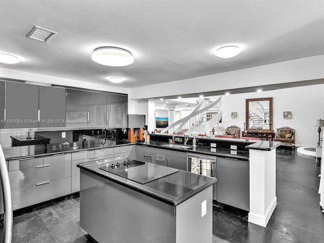 kitchen featuring gray cabinetry, a kitchen island, black electric stovetop, and sink