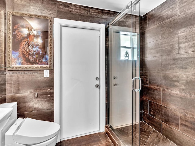 bathroom with tile walls, an enclosed shower, toilet, and tile floors