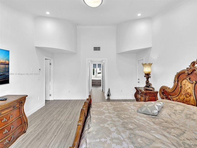 bedroom with light hardwood / wood-style flooring and a high ceiling