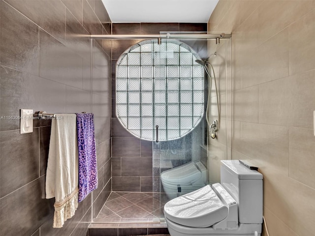 bathroom with tile walls, toilet, and a shower with door