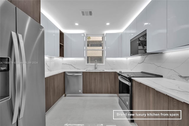 kitchen with backsplash, stainless steel appliances, light tile floors, and light stone counters