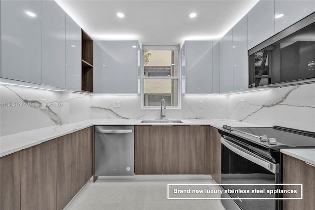 kitchen with light stone counters, backsplash, stainless steel appliances, sink, and light tile floors