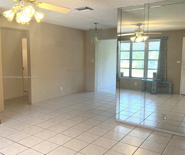 tiled empty room with ceiling fan and a textured ceiling