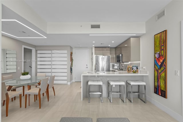 kitchen featuring kitchen peninsula, a kitchen breakfast bar, stainless steel appliances, sink, and gray cabinets