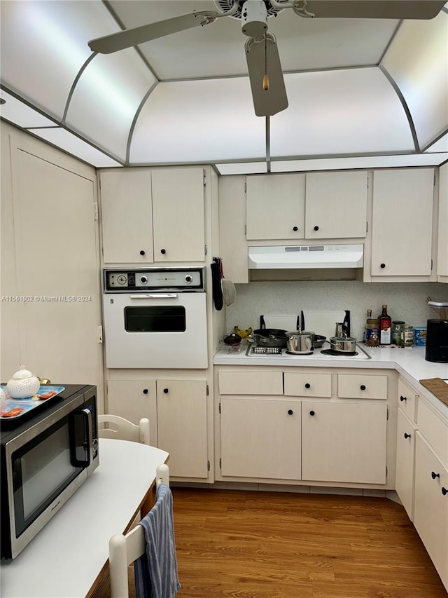 kitchen featuring ceiling fan, oven, and light wood-type flooring