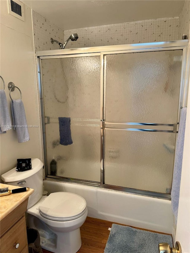 full bathroom with toilet, hardwood / wood-style floors, vanity, and bath / shower combo with glass door