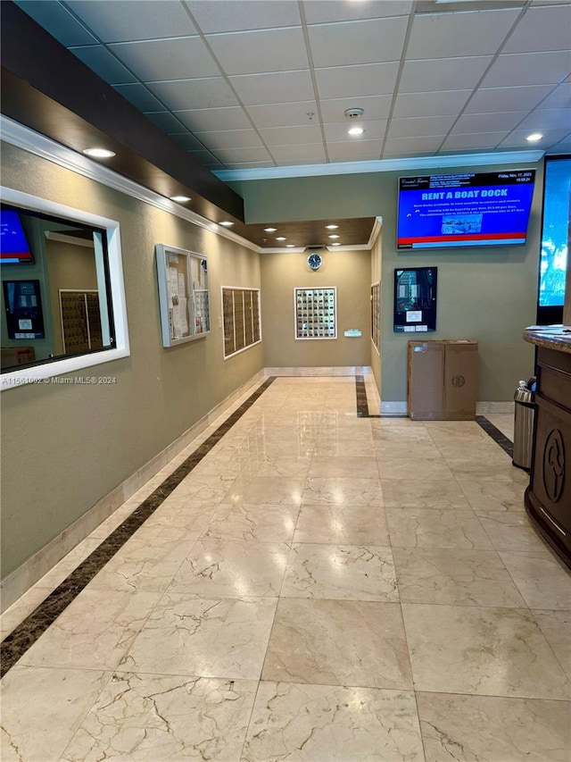 hall with light tile floors and a drop ceiling