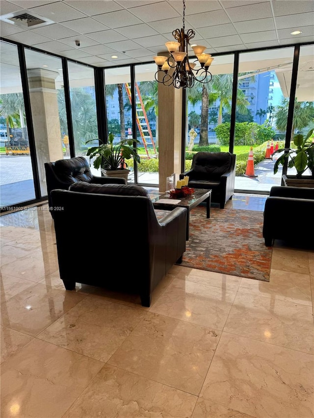 living room featuring a paneled ceiling, light tile floors, floor to ceiling windows, and a notable chandelier