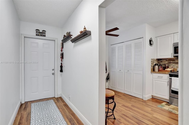 entryway featuring a textured ceiling, ceiling fan, and light wood-type flooring