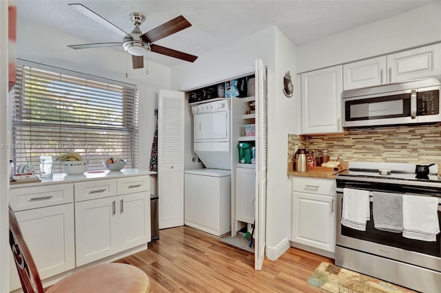 kitchen featuring white cabinets, appliances with stainless steel finishes, and stacked washer and clothes dryer