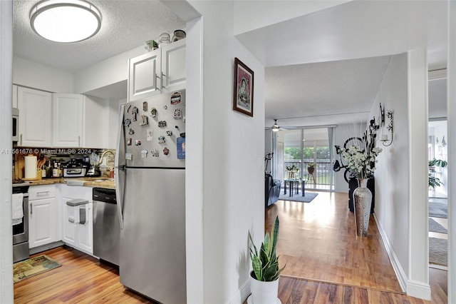 kitchen with ceiling fan, white cabinets, appliances with stainless steel finishes, and light hardwood / wood-style flooring