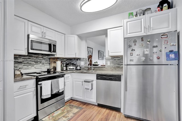 kitchen featuring tasteful backsplash, light hardwood / wood-style flooring, appliances with stainless steel finishes, white cabinetry, and sink