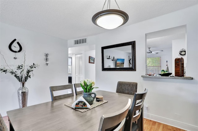 dining space featuring light hardwood / wood-style floors, ceiling fan, and a textured ceiling