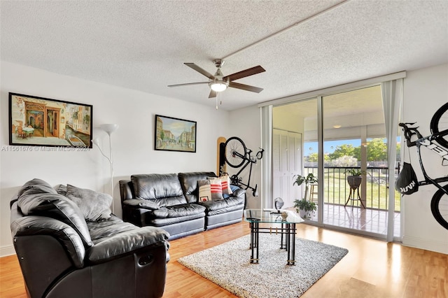 living room featuring light hardwood / wood-style floors, a textured ceiling, and ceiling fan