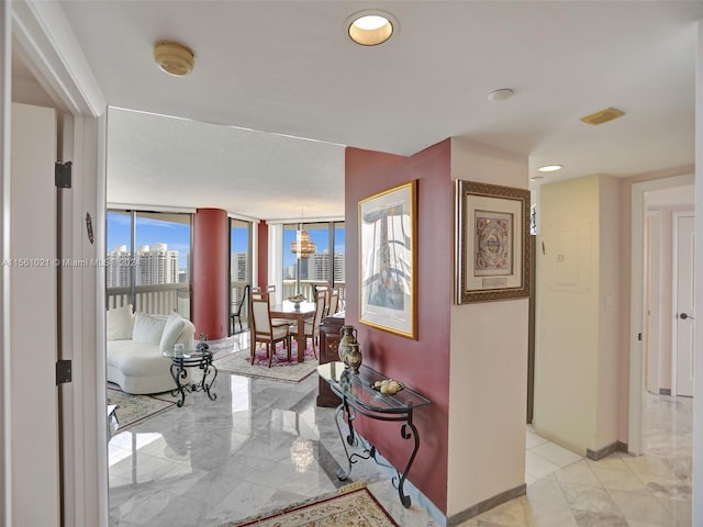 hallway featuring floor to ceiling windows, a chandelier, and light tile floors