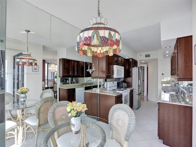 kitchen with dark brown cabinets, light tile floors, pendant lighting, white appliances, and sink