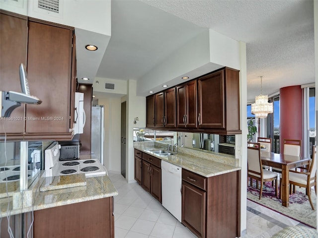 kitchen with decorative light fixtures, white appliances, sink, and light stone counters