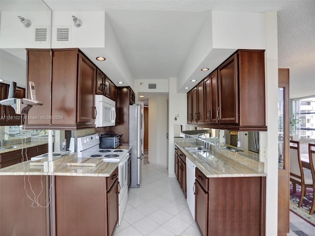 kitchen featuring white appliances, plenty of natural light, light stone counters, and light tile flooring