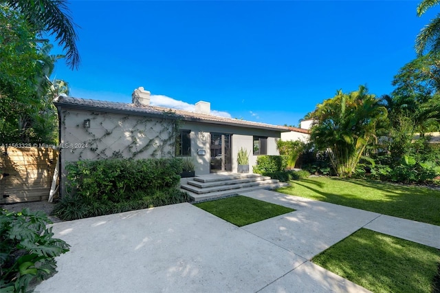 view of front of home with a front yard, fence, a chimney, stucco siding, and a patio area