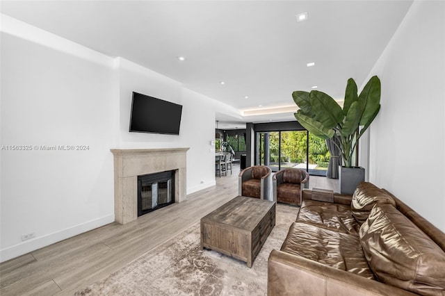 living room featuring recessed lighting, wood finished floors, baseboards, and a high end fireplace